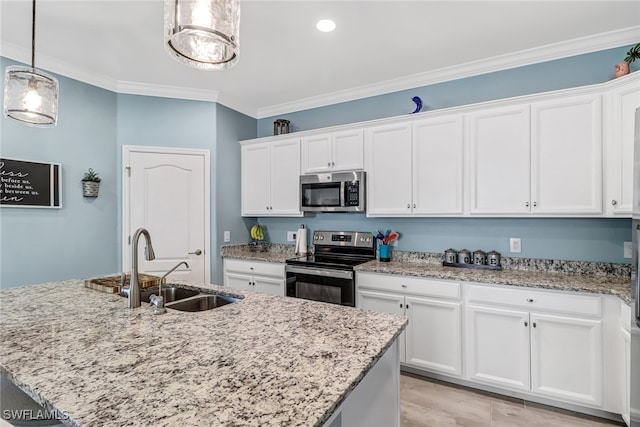 kitchen featuring appliances with stainless steel finishes, sink, decorative light fixtures, white cabinetry, and an island with sink