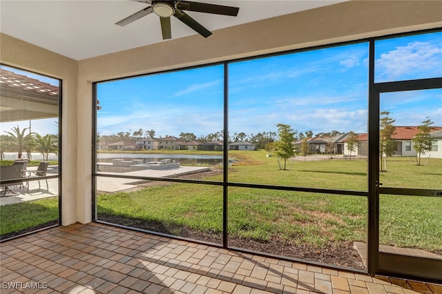 unfurnished sunroom with ceiling fan and a water view