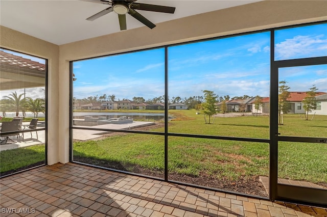 unfurnished sunroom featuring a water view and ceiling fan