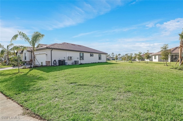 view of side of property with a lawn, a garage, and central AC