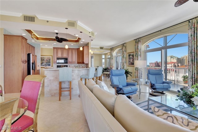 living room with a tray ceiling, crown molding, ceiling fan, and light tile patterned flooring