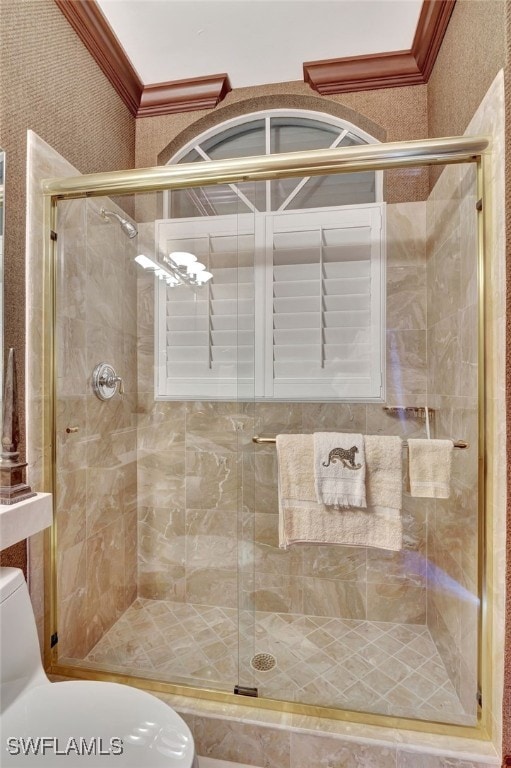 bathroom with crown molding, toilet, and a shower with door