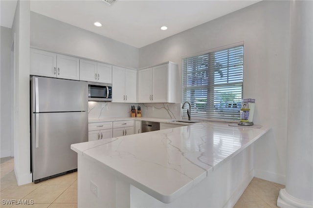 kitchen with light tile patterned flooring, sink, white cabinetry, appliances with stainless steel finishes, and kitchen peninsula