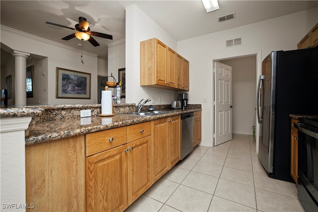 kitchen featuring appliances with stainless steel finishes, crown molding, dark stone counters, decorative columns, and sink