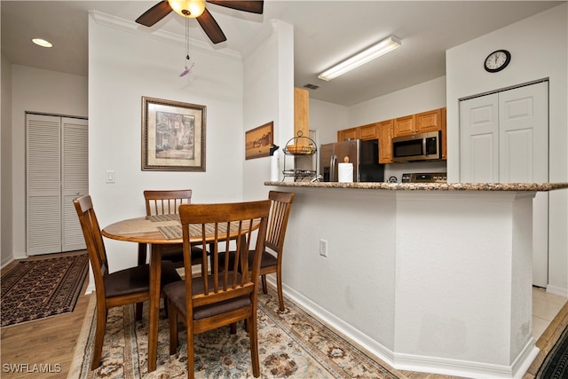 dining area featuring light hardwood / wood-style floors, ornamental molding, and ceiling fan