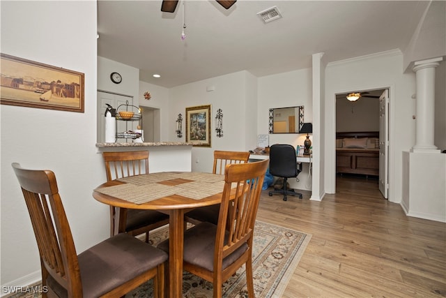 dining area featuring ceiling fan, light wood-type flooring, crown molding, and ornate columns