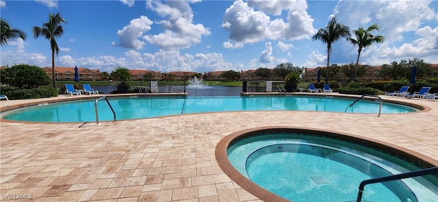 view of swimming pool with a water view, a community hot tub, and a patio area