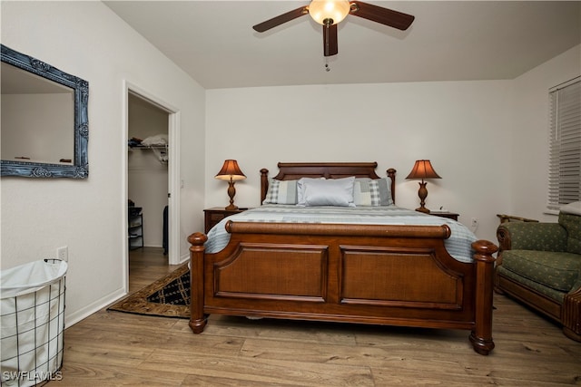 bedroom with wood-type flooring, a spacious closet, ceiling fan, and a closet