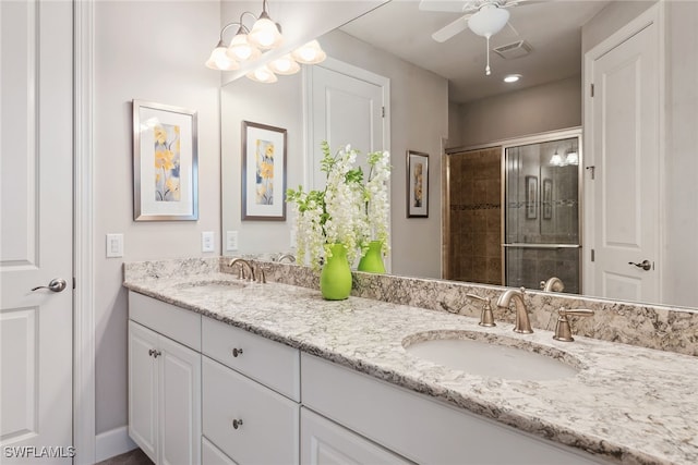 bathroom featuring ceiling fan with notable chandelier, vanity, and a tile shower