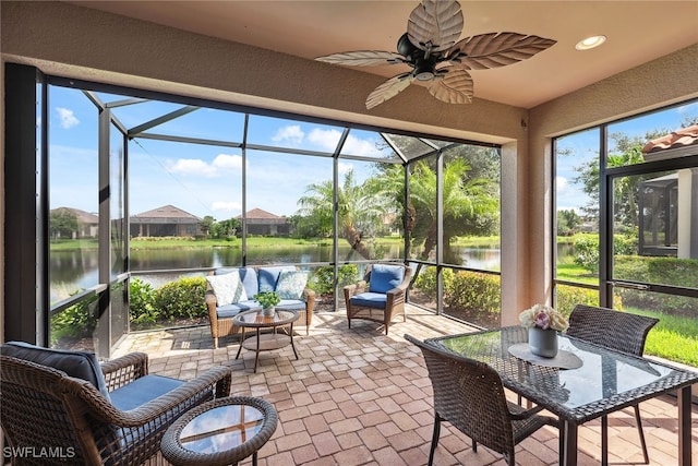 sunroom / solarium featuring a water view and ceiling fan