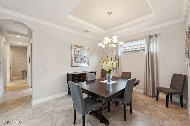 dining area with ornamental molding, a tray ceiling, and a notable chandelier