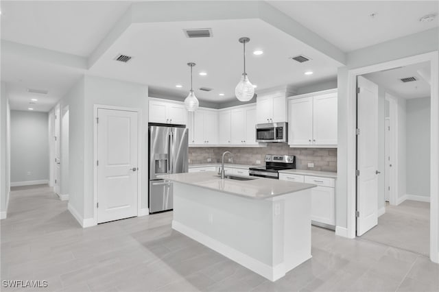 kitchen with decorative light fixtures, an island with sink, sink, appliances with stainless steel finishes, and white cabinets