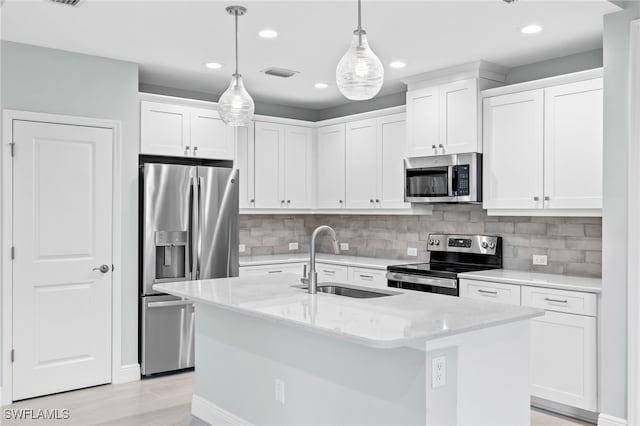 kitchen featuring white cabinets, a kitchen island with sink, stainless steel appliances, and sink