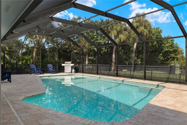 view of pool featuring glass enclosure, area for grilling, and a patio area