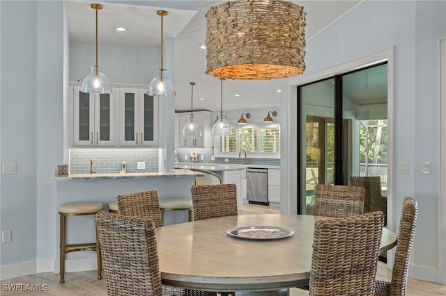 dining area featuring indoor wet bar, light wood-type flooring, and ornamental molding