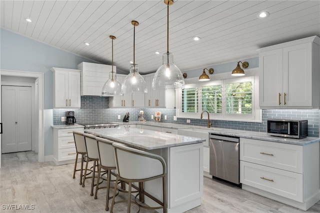 kitchen featuring white cabinets, backsplash, a kitchen island, stainless steel appliances, and decorative light fixtures