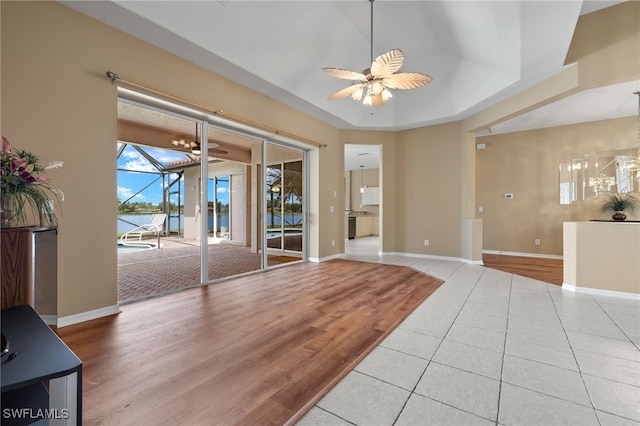 interior space featuring light tile patterned floors, ceiling fan, and a tray ceiling