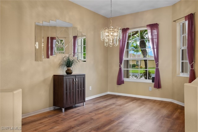 2249 Valencia Lakes Cir, Naples, FL 34120 - unfurnished dining area featuring wood finished floors, a chandelier, and baseboards