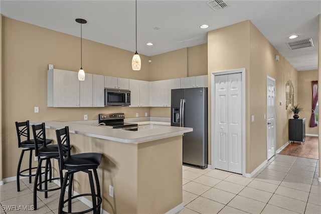 kitchen with stainless steel appliances, decorative light fixtures, light tile patterned floors, kitchen peninsula, and a breakfast bar