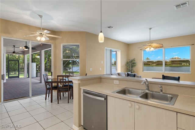 kitchen featuring stainless steel dishwasher, pendant lighting, sink, light tile patterned flooring, and a water view