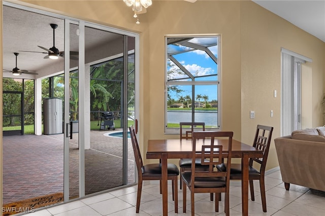 dining area with ceiling fan, a water view, light tile patterned flooring, and a textured ceiling