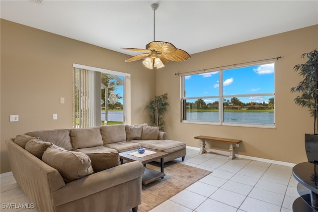 tiled living room featuring ceiling fan and a water view