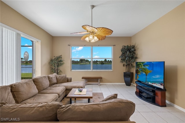 tiled living room featuring ceiling fan, a healthy amount of sunlight, and a water view