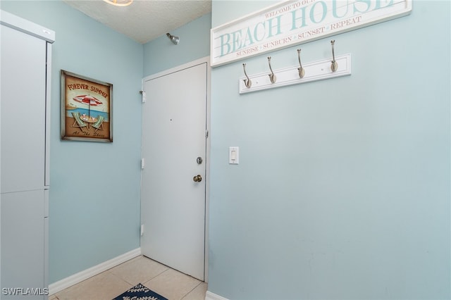 doorway with a textured ceiling and light tile patterned floors