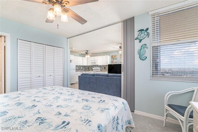 carpeted bedroom with a closet, ceiling fan, white fridge, and a textured ceiling