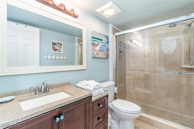 bathroom with walk in shower, vanity, and toilet