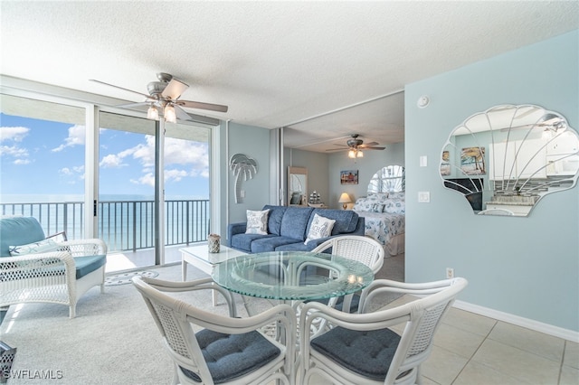 dining room with a water view, ceiling fan, light tile patterned floors, and a textured ceiling