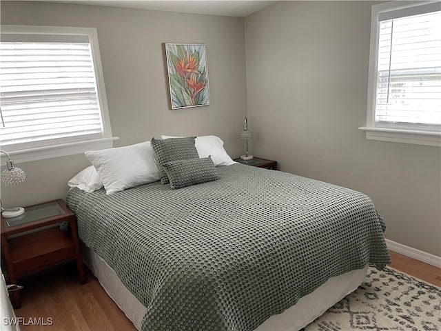 bedroom with multiple windows and dark hardwood / wood-style flooring