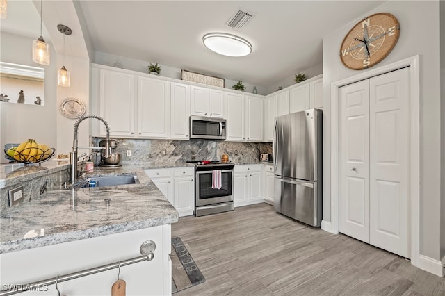 kitchen with appliances with stainless steel finishes, light hardwood / wood-style floors, sink, light stone counters, and white cabinets