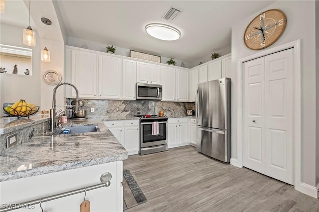 11490 Axis Deer Ln, Fort Myers, FL 33966 - kitchen with stainless steel appliances, white cabinetry, decorative backsplash, and light wood finished floors