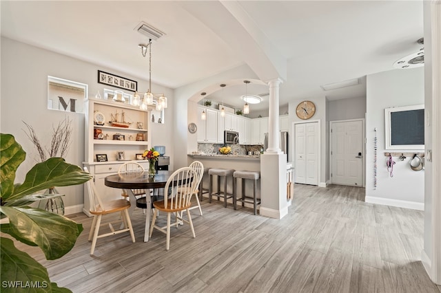 dining space featuring light hardwood / wood-style floors, ceiling fan, and ornate columns