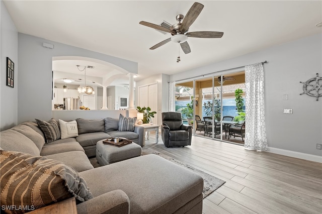 living room with ceiling fan with notable chandelier and light hardwood / wood-style flooring