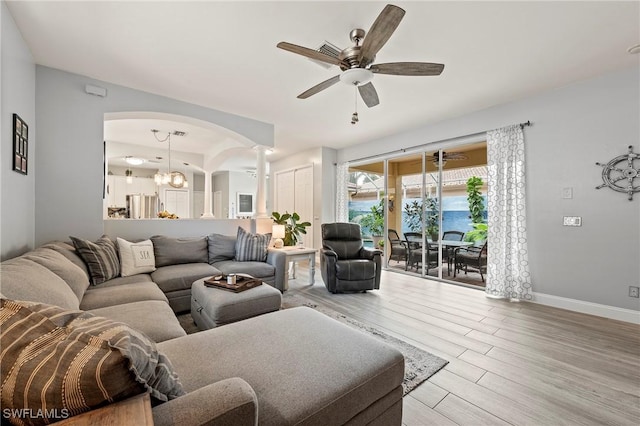 11490 Axis Deer Ln, Fort Myers, FL 33966 - living room with arched walkways, wood finished floors, a chandelier, a ceiling fan, and ornate columns