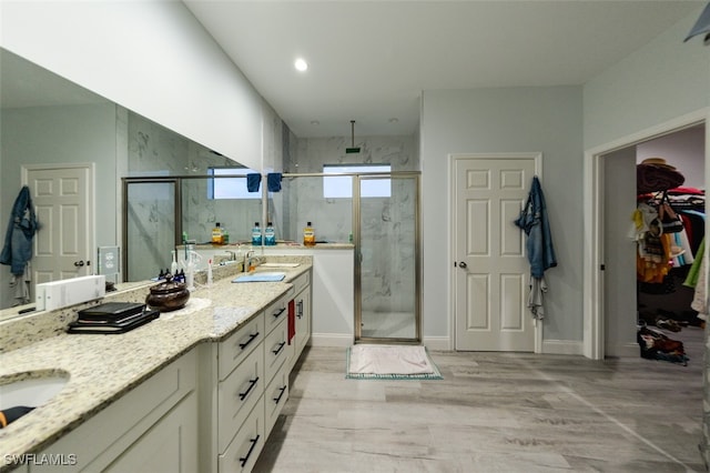 bathroom featuring walk in shower, vanity, and wood-type flooring