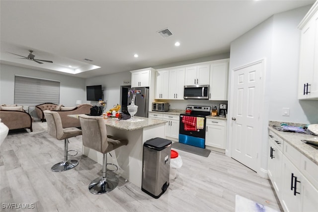 kitchen with light stone counters, white cabinetry, and stainless steel appliances