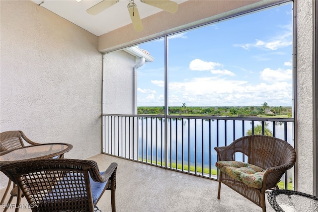 balcony featuring a water view and ceiling fan