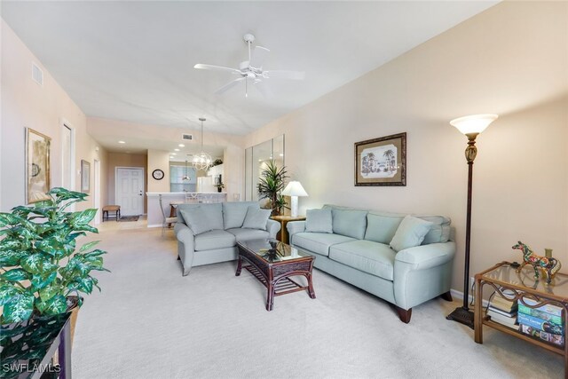 living room featuring light carpet and ceiling fan with notable chandelier