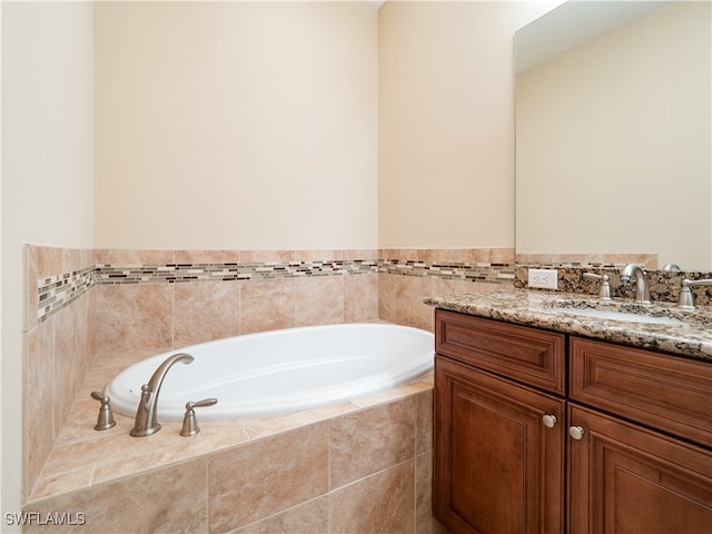 bathroom with vanity and tiled bath