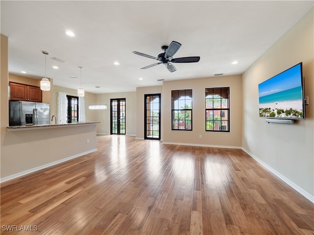 unfurnished living room featuring ceiling fan, sink, and light hardwood / wood-style flooring