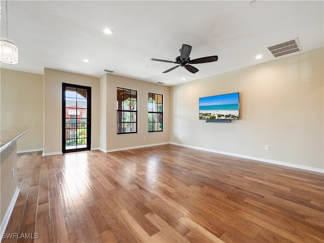 unfurnished living room with hardwood / wood-style floors and ceiling fan with notable chandelier