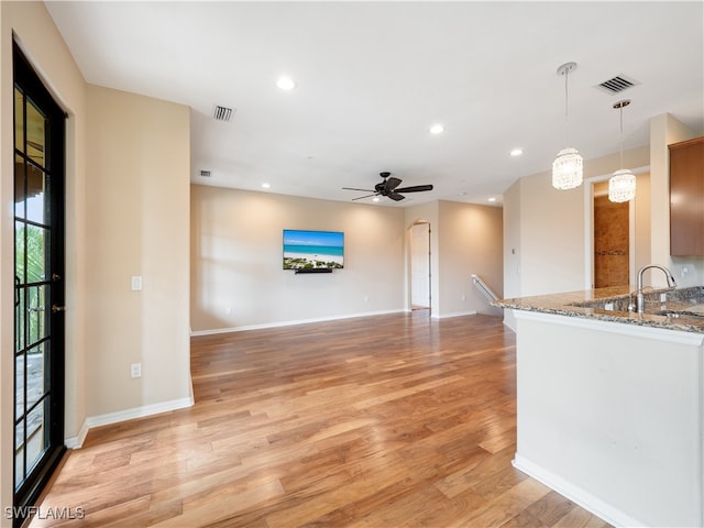 unfurnished living room with sink, ceiling fan, and light hardwood / wood-style floors