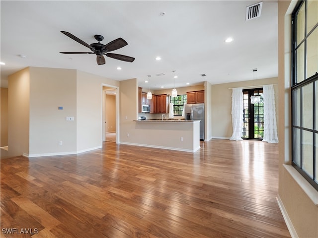 unfurnished living room featuring light hardwood / wood-style flooring, ceiling fan, and sink