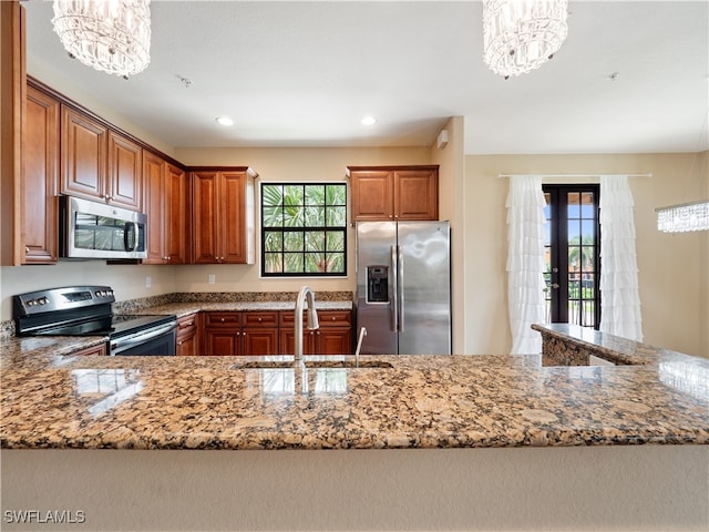 kitchen featuring decorative light fixtures, appliances with stainless steel finishes, an inviting chandelier, and sink