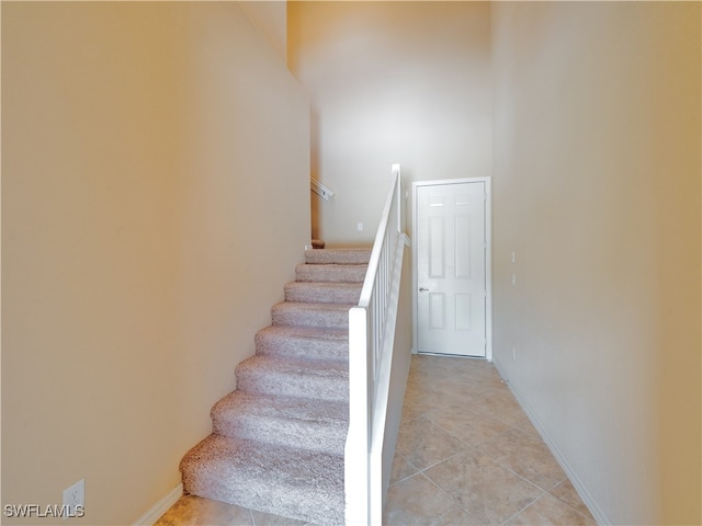 staircase featuring tile patterned flooring and a towering ceiling