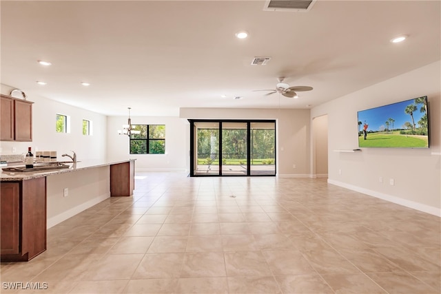 kitchen featuring light stone countertops, decorative light fixtures, ceiling fan with notable chandelier, and light tile patterned floors