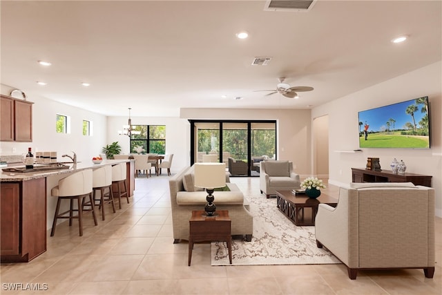 living room with ceiling fan with notable chandelier and light tile patterned floors